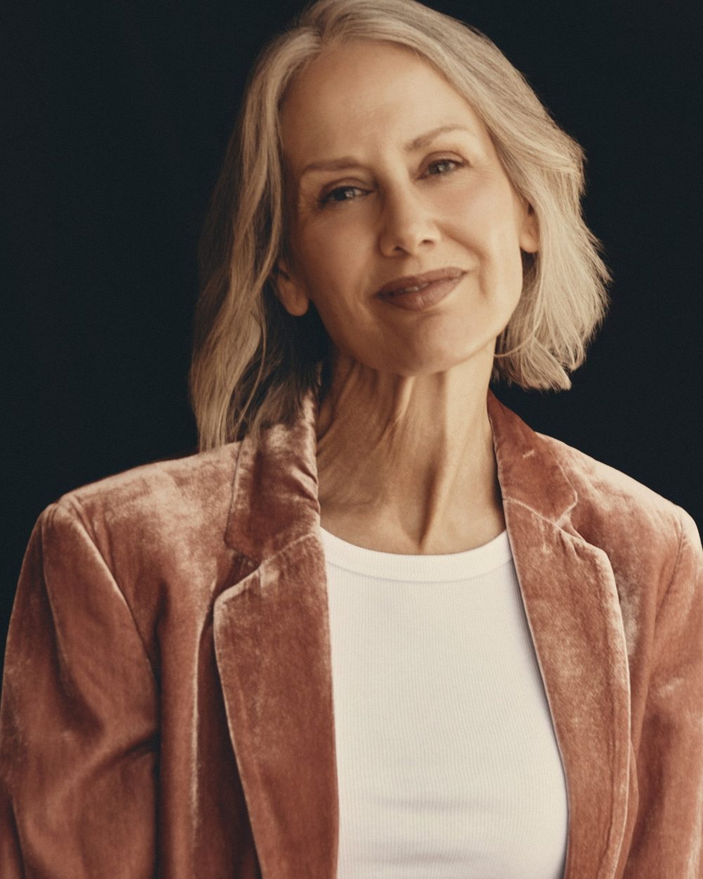 Portrait of Samantha Foreman smiling, in a dusty-rose velvet jacket over a white ribbed tank
